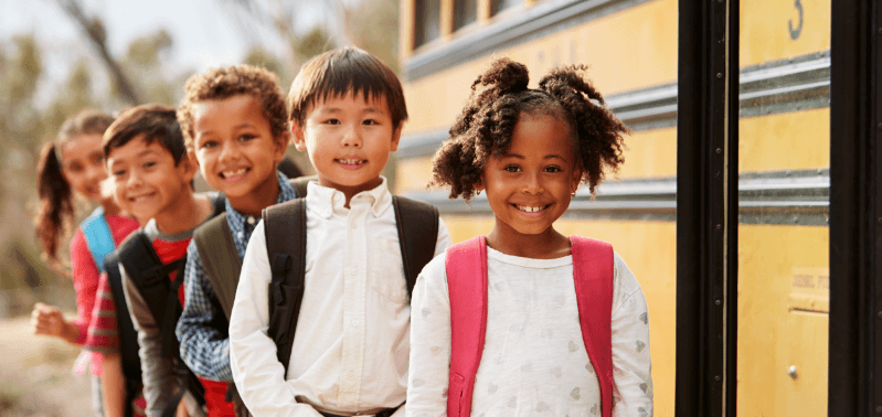 5 Children smiling and waiting for school bus